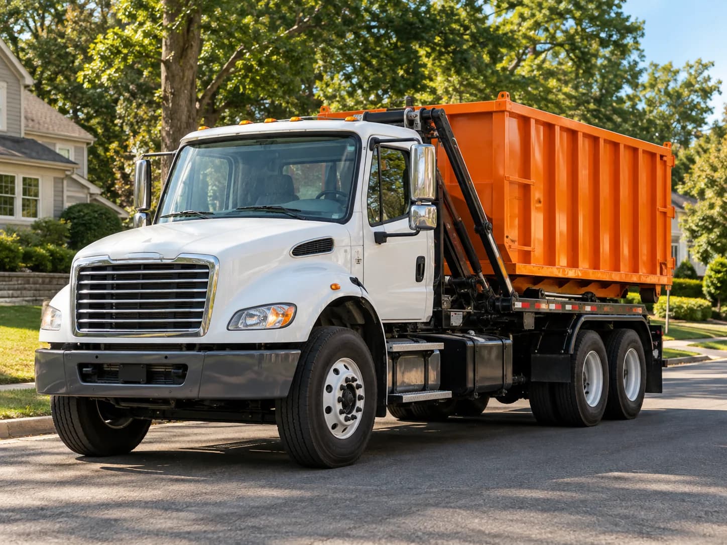 White roll-off truck carrying an orange dumpster